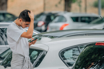 young man with mobile phone looking at cars