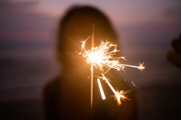 Sticker - woman holding sparkles celebrating on tropical beach