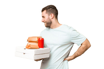 Poster - Young handsome blonde man holding pizzas and burgers over isolated background suffering from backache for having made an effort