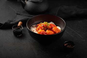 Wall Mural - Portion of asian sweet and sour shrimp with rice on black background