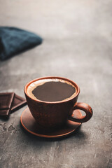 Wall Mural - Black coffee drink in a clay cup and coffee beans in a spoon on dark background