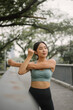 © sarayutsridee - Asian happy woman exercise in park on morning. Healthy female wearing sportswear and stretching body before running in outdoors. wellness lifestyle, outside activities.