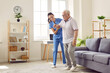 © Studio Romantic - Smiling caregiver helping senior man to stand up and walk. Female nurse assisting her elderly patient suffering from mental disability in nursing home. Disabled old man trying to walk with assistance