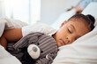 © David L/peopleimages.com - Peace, morning and wellness of black child sleeping in cozy bed with toy teddy in home on the weekend. Relax, sleep and health of kid dreaming in comfortable home bedroom with teddy bear.
