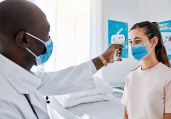 Wall Mural - Covid temperature testing at the hospital by a doctor of a female patient wearing masks and using an infrared thermometer. Medical professional checking a female for covid19 virus or infection