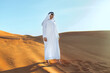 Arabian sheikh in long white dress closeup in the middle of Dubai desert.