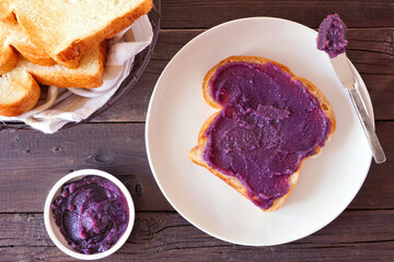 Sticker - Toast with ube halaya jam. Sweet, trendy, purple yam spread. Top view table scene on a dark wood background.