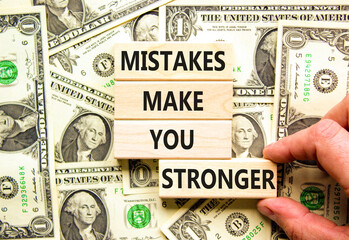 Wall Mural - Mistake make stronger symbol. Concept words Mistakes make you stronger on wooden blocks. Beautiful background from dollar bills. Businessman hand. Business mistake make stronger concept. Copy space.