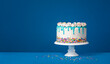 White birthday drip cake with teal ganache over dark blue background