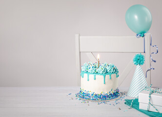 Wall Mural - Blue Birthday cake, presents, hats and balloons over light grey background.