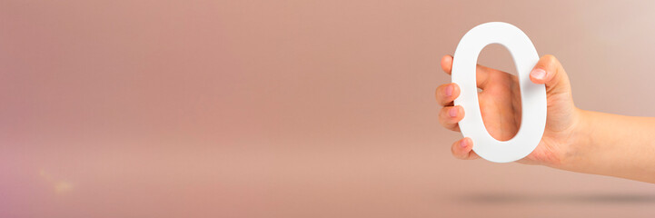 Fototapete - Numeral zero in hand. A hand holds a white number zero on a red background with copy space. Zero concept, 0 percent interest rate, minimum air emissions, cost or credit no increase.