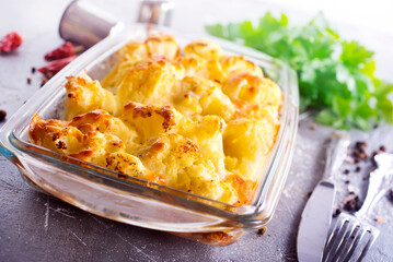 Wall Mural - Savory food: baked cauliflower with cheese, eggs and cream close-up in a baking dish on a table.