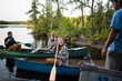 © Cavan Images - Man looking at friends canoeing on lake against trees