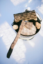 High Angle View Of Rusty Axe And Wood In Bucket On Snowy Field