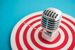 © pla2na - Retro microphone on center of target blue background copy space. Focus on customer feedback, satisfaction, review need for organization improvement and development. Leadership management and strategy.