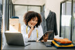 © Nuttapong punna - African tailor woman working on clothes in tailoring atelier.  beautiful female fashion designer smile and after success in studio