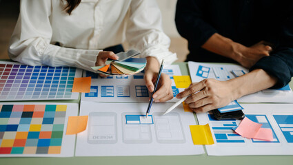  UX developer and ui designer brainstorming about mobile app interface wireframe design with customer breif and color code at office..