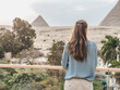 Stylish woman against the background of the Giza pyramid complex. Clear, sunny day, blue sky. Vacation and travel concept