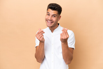 Wall Mural - Young caucasian man isolated on beige background making money gesture