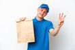 © luismolinero - Young Brazilian man taking a bag of takeaway food isolated on white background happy and counting three with fingers