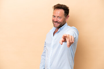 Middle age caucasian man isolated on beige background pointing front with happy expression