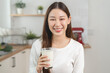 © Pormezz - Young Asian woman holding a glass of milk in the kitchen