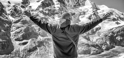 Poster - Man embracing nature on a beautiful summer day with snowy mountains on the background.