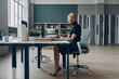 © gstockstudio - Serious young businesswoman using laptop while sitting at her working place in office