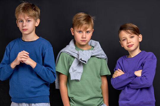 self assured children in casual stylish clothes looking at camera against black background gang is r