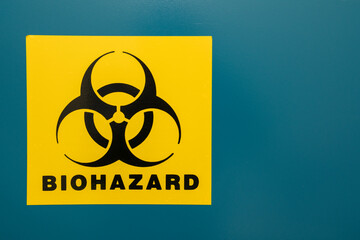 Wall Mural - Blue background with a yellow-black sticker with biohazard sign.