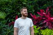 © Евгений Шемякин - Portrait of happy young bearded man with beard breathing deep, inhale fresh air on natural background, green wall with leaves, flower in tropical country in garden. Eco, ecological concept.