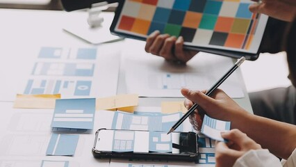 Close up ux developer and ui designer brainstorming about mobile app interface wireframe design on table with customer breif and color code at modern office.Creative digital development agency