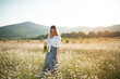 © morrowlight - Beautiful attractive blonde woman pick up chamomile flowers walk in blooming meadow outdoor. Spring season.