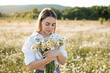 © morrowlight - Beautiful attractive blonde woman 25-27 year old pick up chamomile flowers walk in blooming meadow outdoor. Spring season.