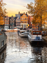 Amsterdam Netherlands, Holland. Dancing Houses Over River Amstel Landmark In Old European City Fall Landscape. House Boats On The Water. Autumn Evening Street
