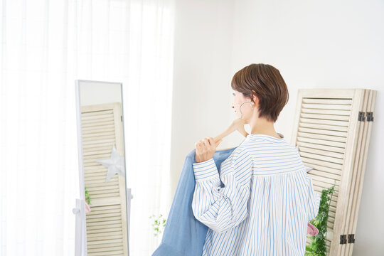 Wall Mural - 家で鏡を見て洋服を選ぶ女性