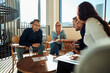© Flamingo Images - Smiling diverse businesspeople going over paperwork during a meeting