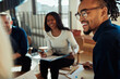 © Flamingo Images - Smiling young African American businessman talking with colleagues at work