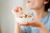 Fototapeta  - ミックスナッツを食べる若い女性　飲食イメージ