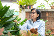 © Supachai - Asian elderly woman taking notes on planting trees in garden at home. Older woman retirement relaxing and use spend their free time on their hobby