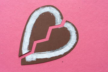 Poster - broken heart or brown paper heart cut in two and arranged on rough pink/red paper