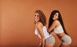 © Flamingo Images - Diverse young female friends in underwear smiling on an orange background