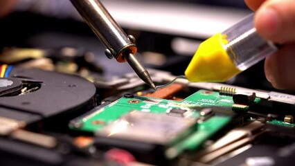 Wall Mural - a man is soldering in a repair shop. repair of the board with a soldering iron