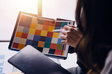 Close up ux developer and ui designer brainstorming about mobile app interface wireframe design on table with customer breif and color code at modern office.Creative digital development agency