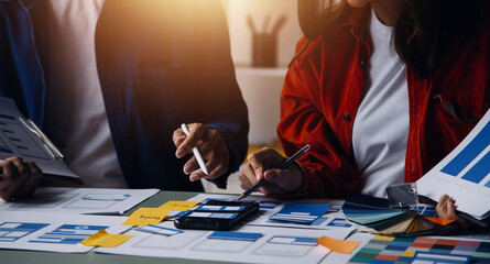 Close up ux developer and ui designer brainstorming about mobile app interface wireframe design on table with customer breif and color code at modern office.Creative digital development agency