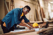 © DJ Creative Studio - Portrait african american man carpenter craftman working in wood factory, small business wood workshop. Timber industry and furniture factory.