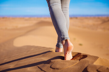 close up view of woman legs walking on sand dune in sahara desert