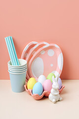 Wall Mural - Cute paper cups and  plates in the shape of  eggs with  Easter eggs, candy and Easter Bunny. Happy Easter. Set of holiday disposable tableware and decorations for party or picnic.