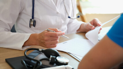 Sticker - Doctor makes notes in document, sitting at table with patient.