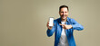 © Moon Safari - Handsome mid adult man dressed in denim jacket laughing and pointing at smart phone's blank screen isolated against gray background